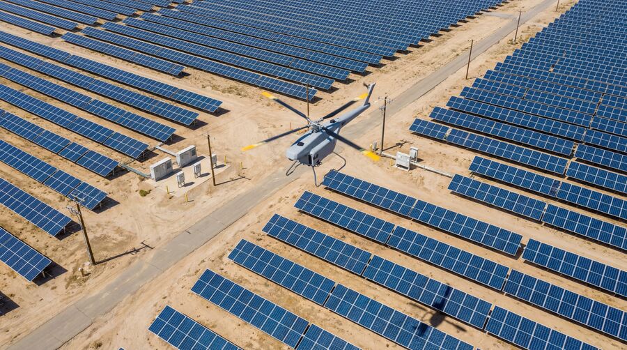 Autonomous inspection drone flying over a utility-scale solar farm