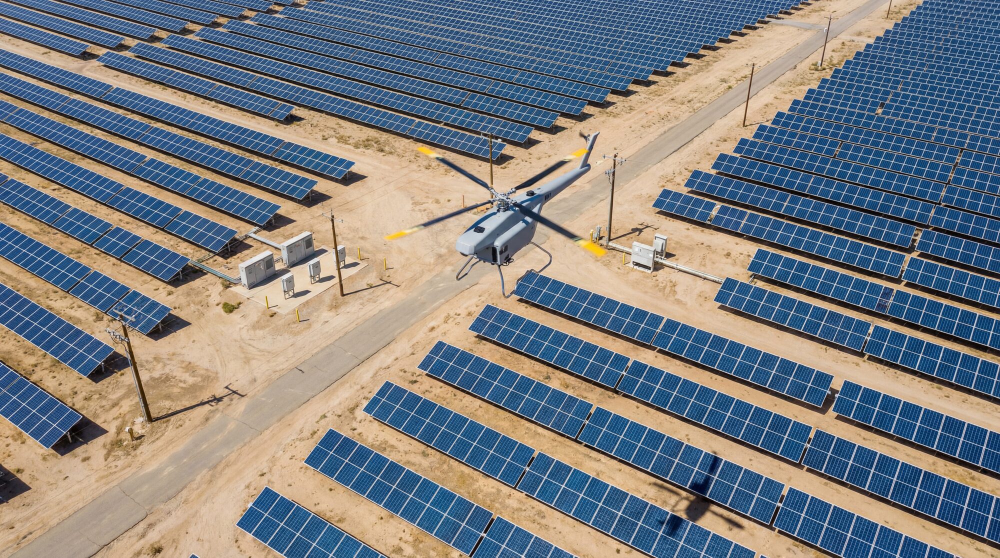 Aerial inspection drone hovering above rows of solar panels at a utility-scale plant